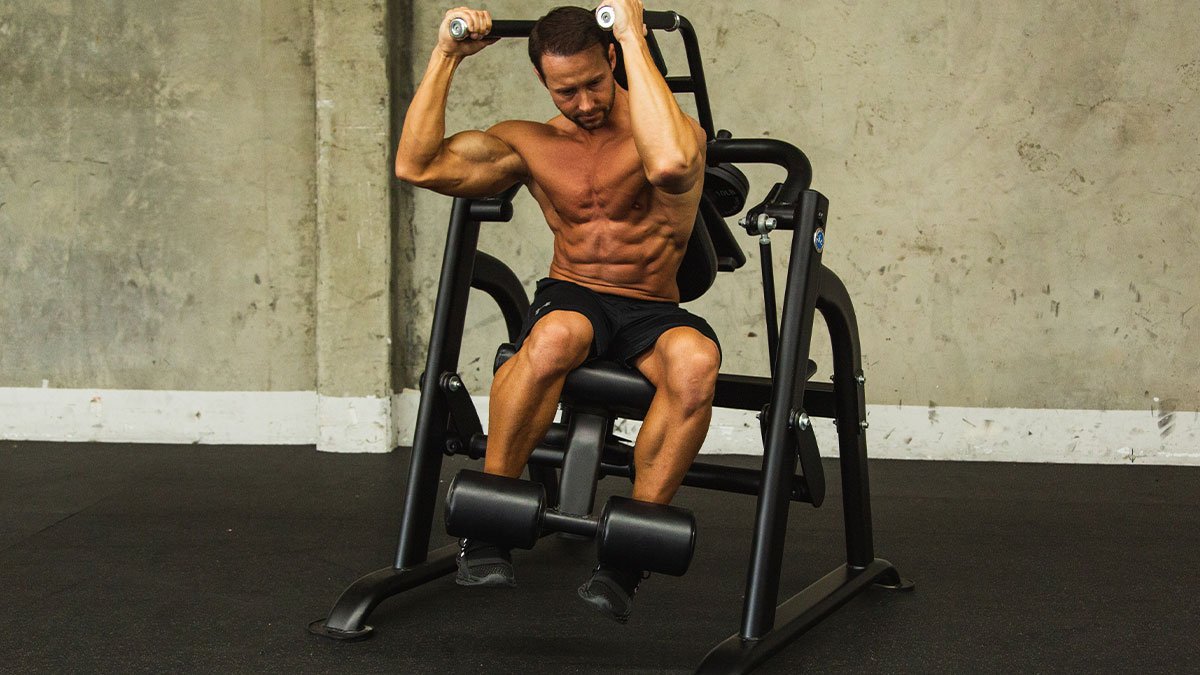 Athlete training on a plate-loaded abdominal crunch machine in a commercial gym