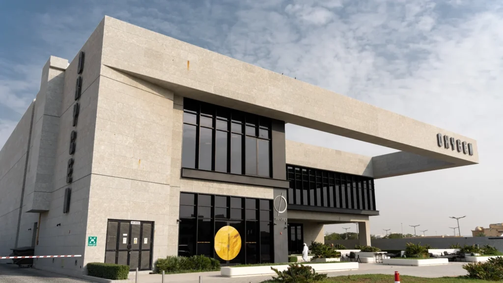Exterior of Oxygen Gym in Saudi Arabia, a stone-clad building with a cantilevered roof and black glass facade
